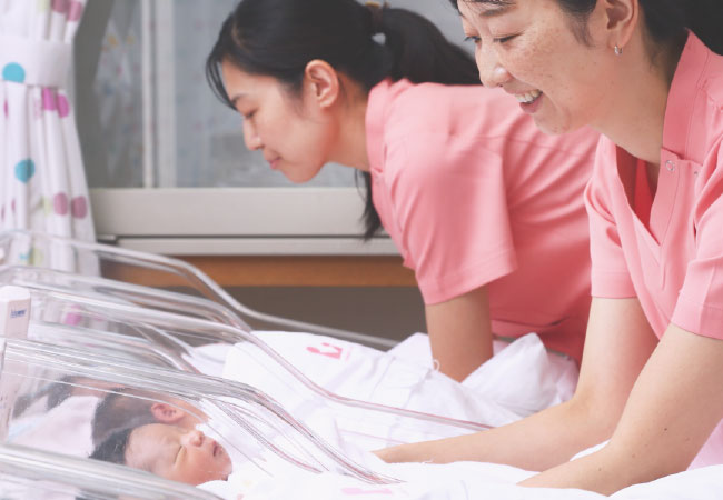 新生児室の赤ちゃんと助産師